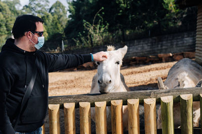 Side view of young man with horse on field