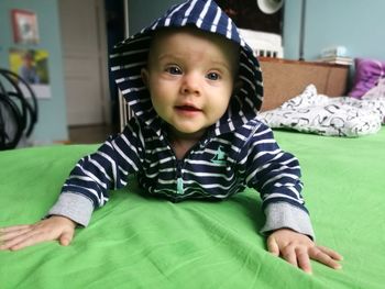 Portrait of cute baby girl lying on bed