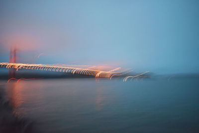 Scenic view of bay against foggy sky at sunrise