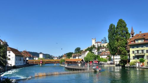 River amidst buildings against clear blue sky