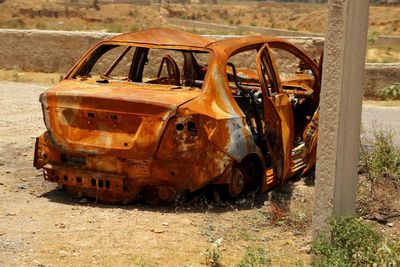 Abandoned rusty car on field