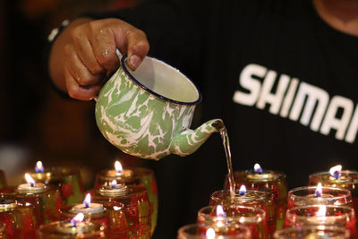 Close-up of hand holding lit candles