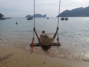 Rear view of woman sitting on beach