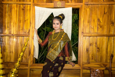 Portrait of smiling young woman sitting on window sill at home