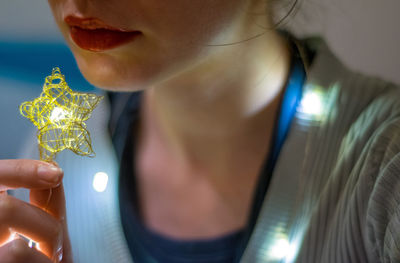 Close-up of woman holding illuminated star shape
