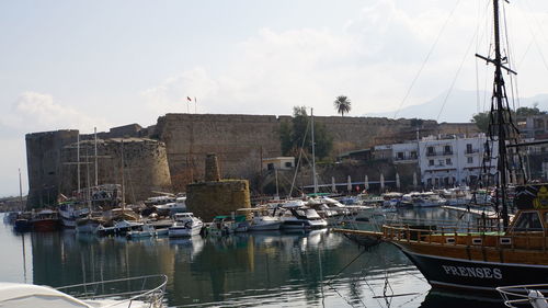 Sailboats moored at harbor against buildings in city