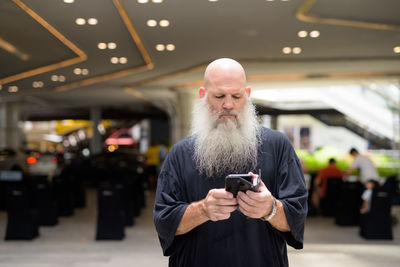 Man using mobile phone while standing on laptop