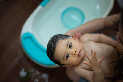 High angle view of mother holding cute baby girl in bathroom