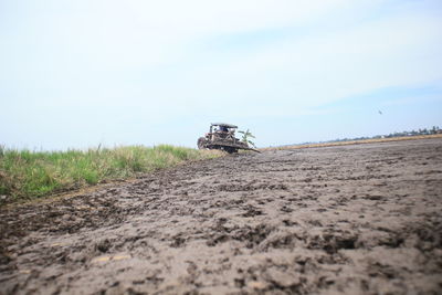 Surface level of dirt road on field against sky
