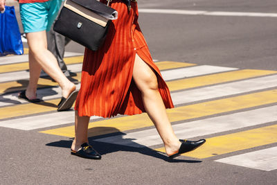 Low section of woman in high heels on road