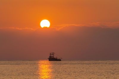 Silhouette ship sailing on sea against sky during sunset