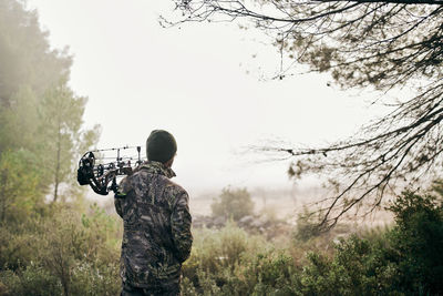 Rear view of man photographing on field