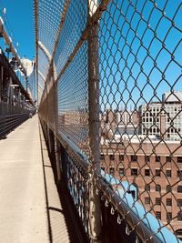 Chainlink fence against sky in city with bike lane over nyc bridge