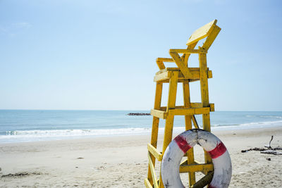 High wooden chair for lifeguard at the beach with seascape and coast in background