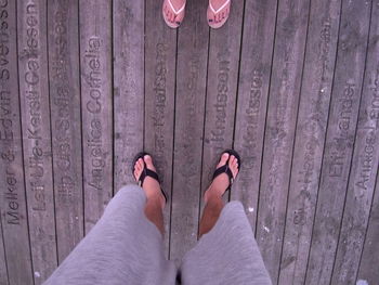 Low section of man standing on wooden footpath