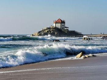 Lighthouse by sea against clear sky