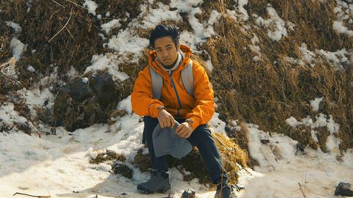 Man sitting on snow covered landscape