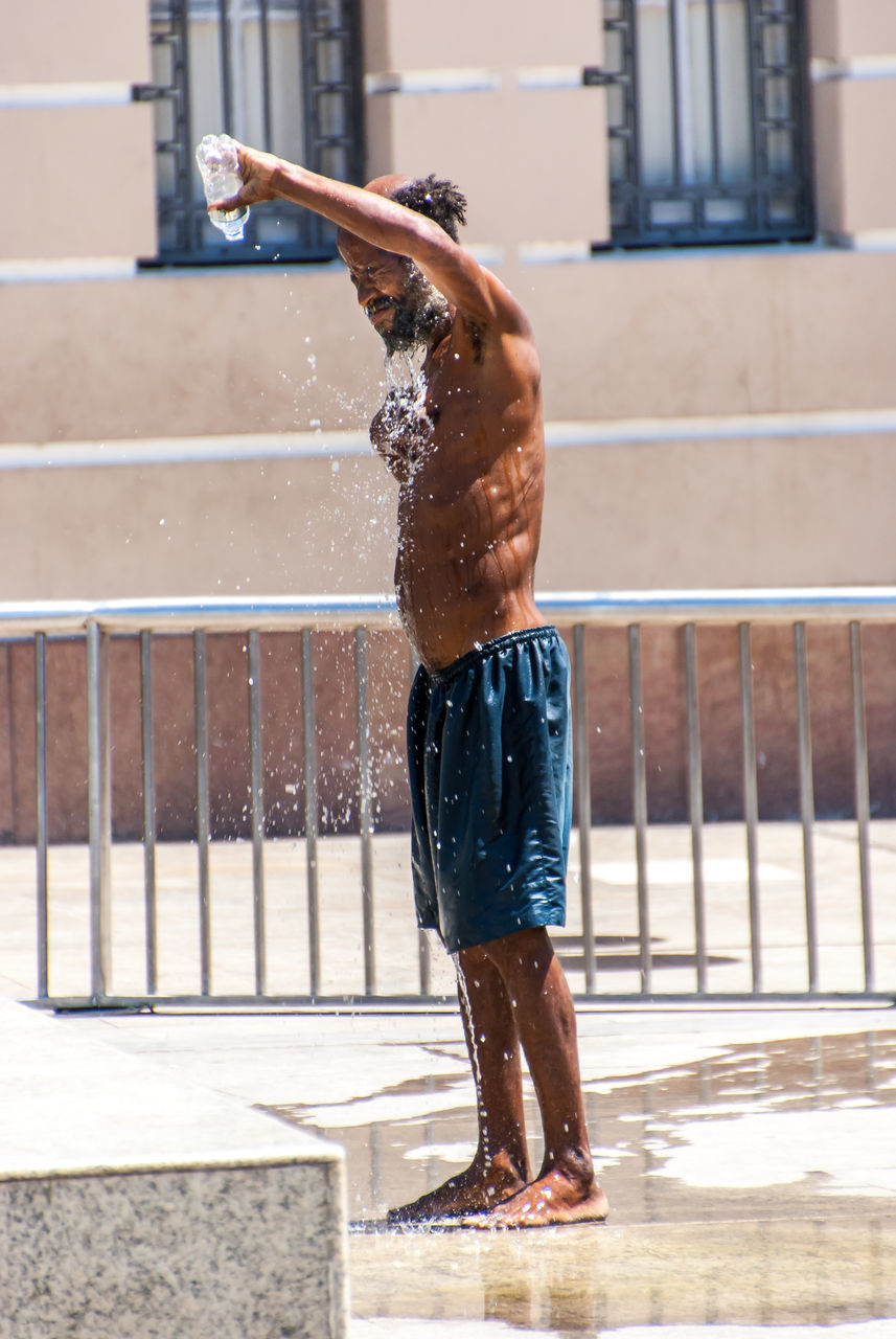 water, child, motion, real people, one person, wet, males, childhood, lifestyles, leisure activity, architecture, shirtless, enjoyment, day, boys, nature, men, full length, outdoors, human arm, spraying, swimming pool, arms raised