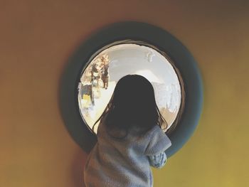 Rear view of girl looking through glass window