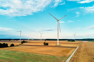 Windmills on field against sky