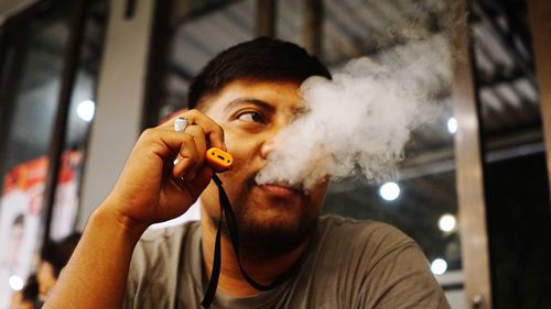 Portrait of young man smoking vape