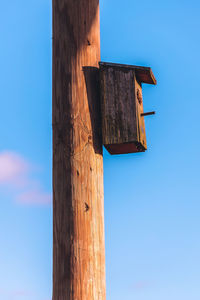 Low angle view of wooden post against sky