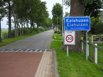 Information sign on road by trees