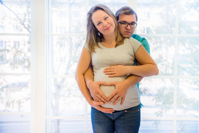 Portrait of couple standing against window