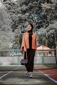 Full length portrait of woman standing in park