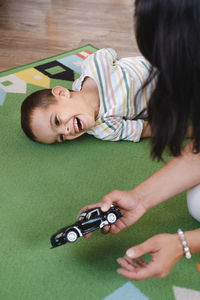 Disabled boy playing toy cars with mother at home. cerebral palsy child entertaining on the mat with