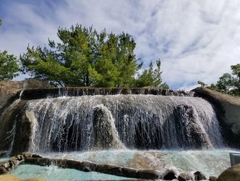 View of waterfall against cloudy sky