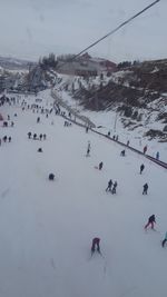 People on snow covered landscape against sky