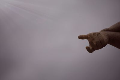 Close-up of hand against sky