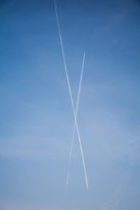 Low angle view of vapor trail against blue sky