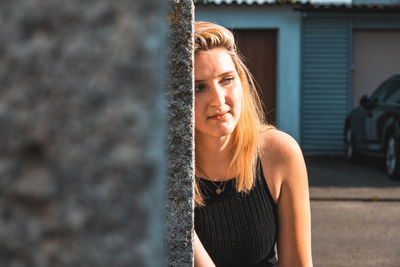 Portrait of young woman standing against wall