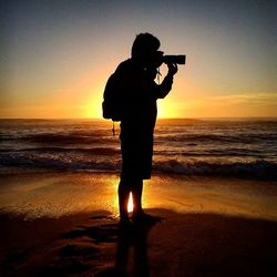 Silhouette of people on beach at sunset