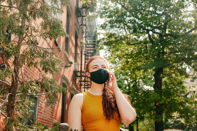 Full length of young woman photographing while standing on tree