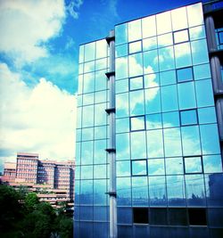 Low angle view of modern building against cloudy sky