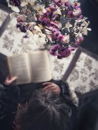 High angle view of woman reading book by purple flowers