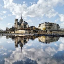 Reflection of building in lake against cloudy sky