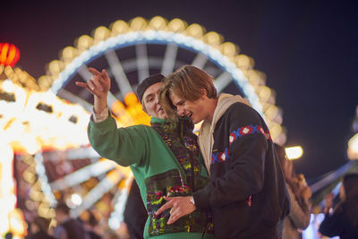 Drunk men standing at amusement park during night