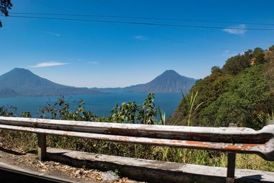 Scenic view of sea in front of mountains against blue sky