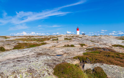 Lighthouse amidst rocks and buildings against sky