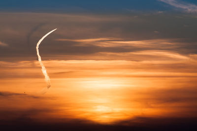 Low angle view of vapor trail in sky during sunset