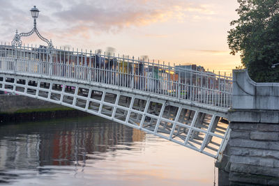 Bridge over river against sky at sunset