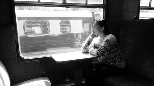 Thoughtful woman sitting by window in train