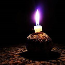 Close-up of lit candle against black background