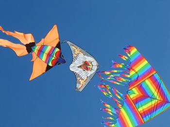 Low angle view of kites against clear blue sky