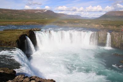 Scenic view of waterfall against sky