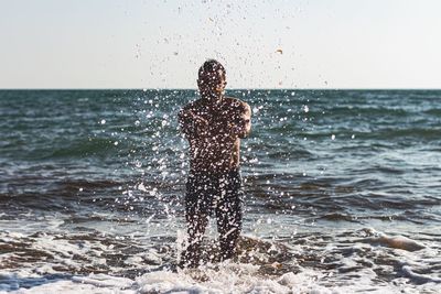 Man standing in sea against clear sky